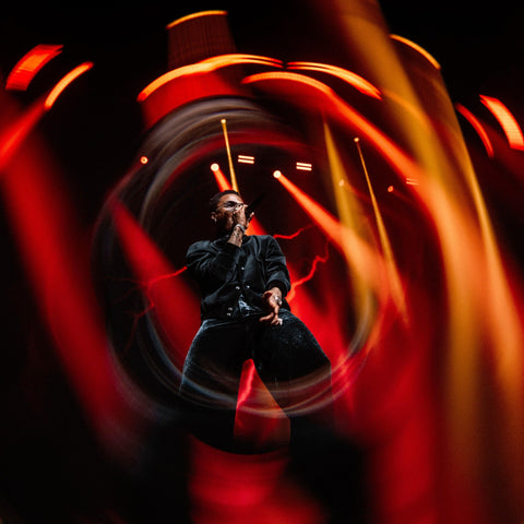 Performer surrounded by warm circular light streaks in a Black Hole concert photograph