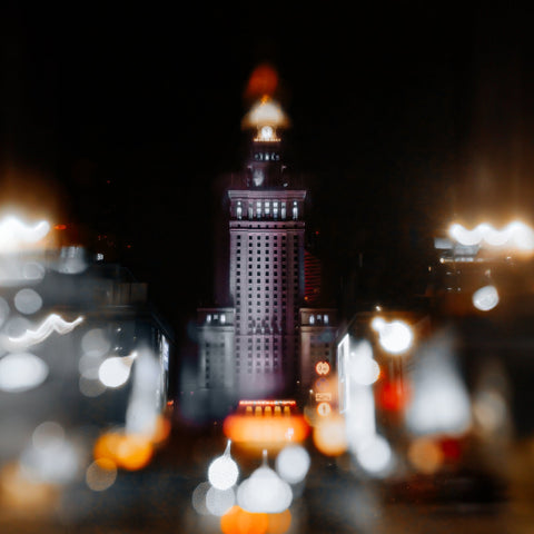 Illuminated city tower against a dark sky with softened lights around the edges