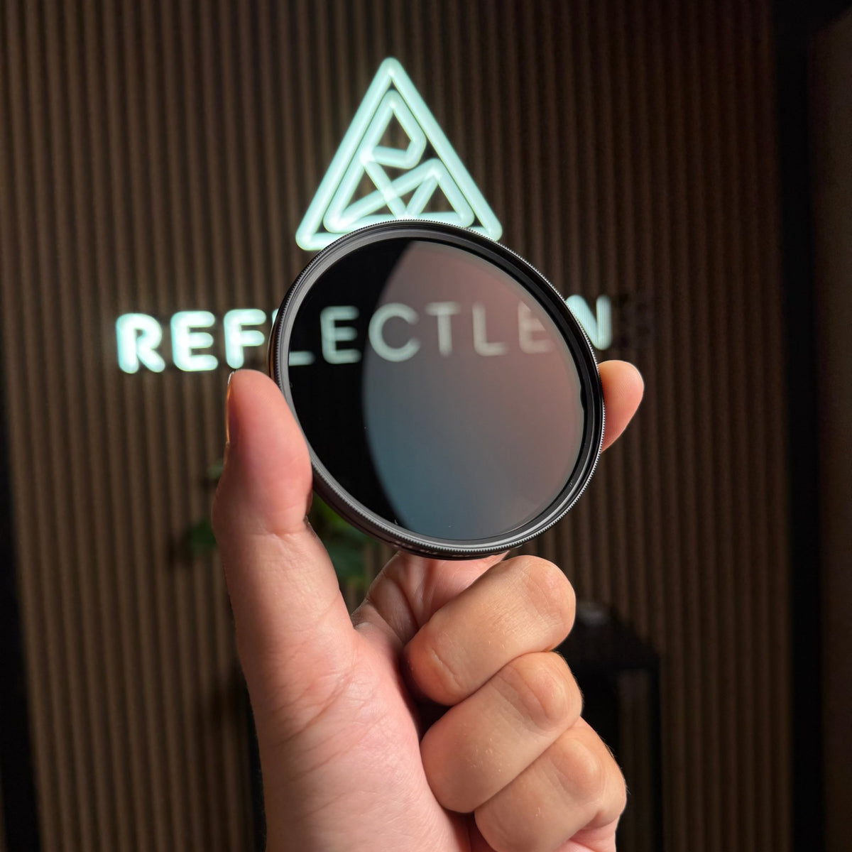 Filtro per fotocamera RFL-VND 2-32 tenuto davanti all’insegna dello showroom REFLECTLENS